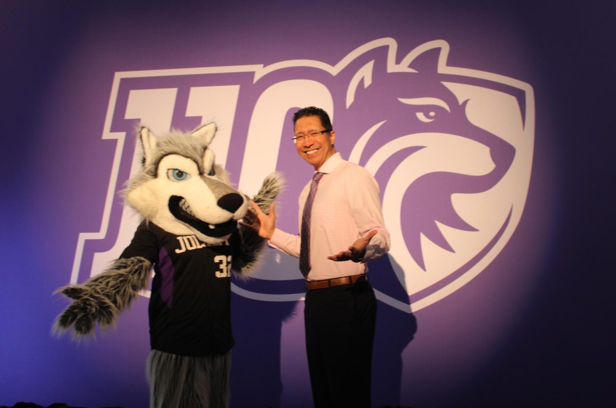 Joliet Junior College President Dr. Clyne Namuo and Wiley the Wolf stand in front of JJC's brand new logo.